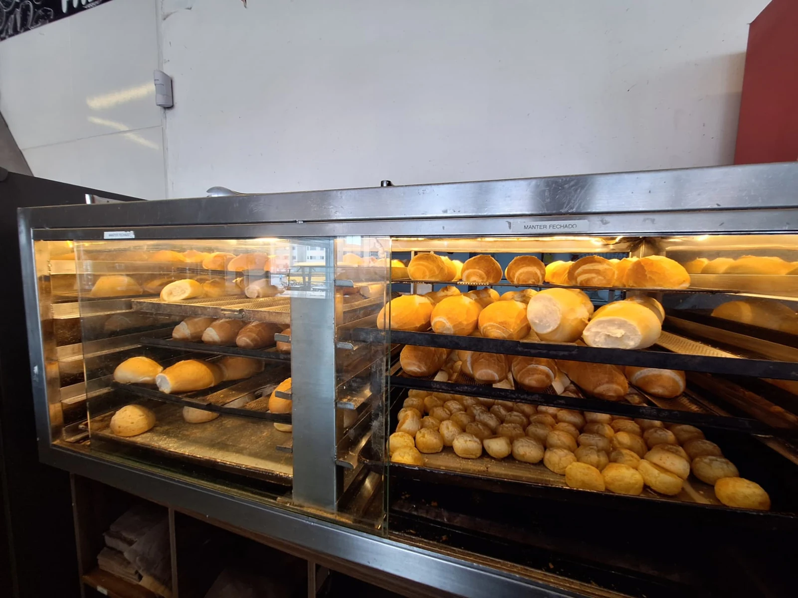 Vitrine aquecida da ManáPan com pão francês nas prateleiras e pão de queijo na bandeja inferior