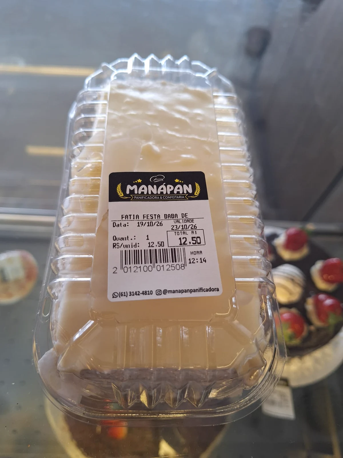 Fatia de bolo de baba de moça da ManáPan embalada para viagem com etiqueta da padaria